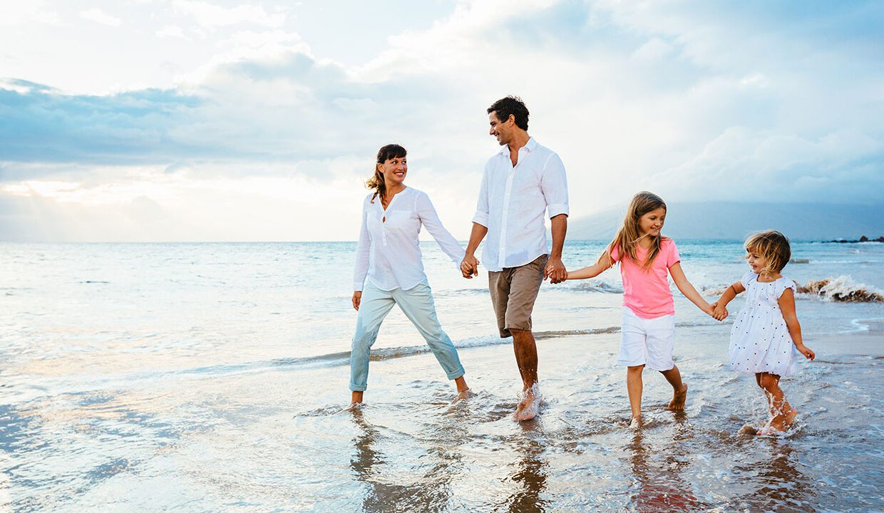 A family walking on the beach holding hands