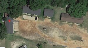 A dirt road with houses and trees in the background.