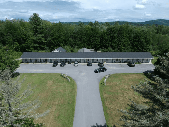 A motel with cars parked in front of it.