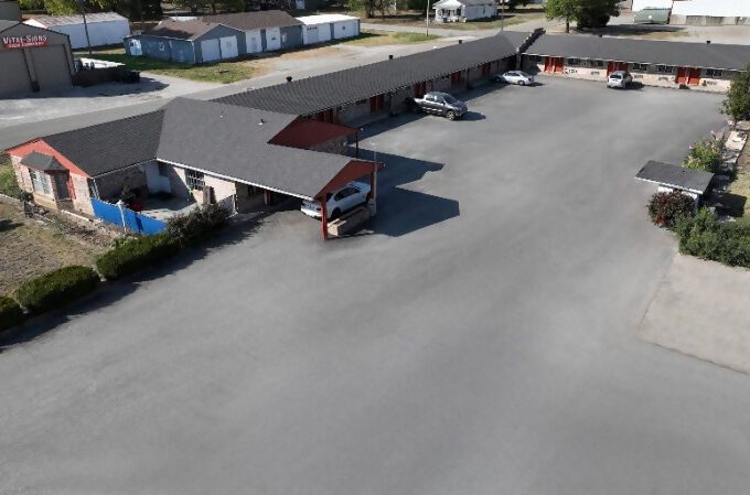 A motel with cars parked in front of it.