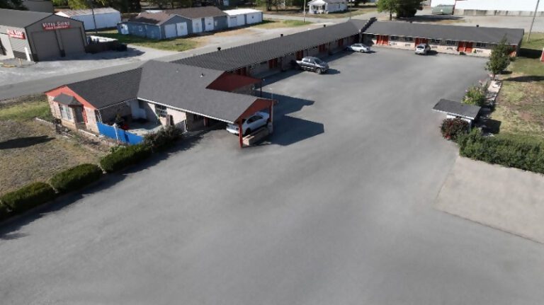 A motel with cars parked in front of it.