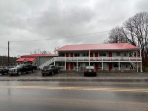 A motel with cars parked on the side of it.